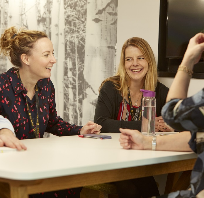 Colleagues laughing in breakout area